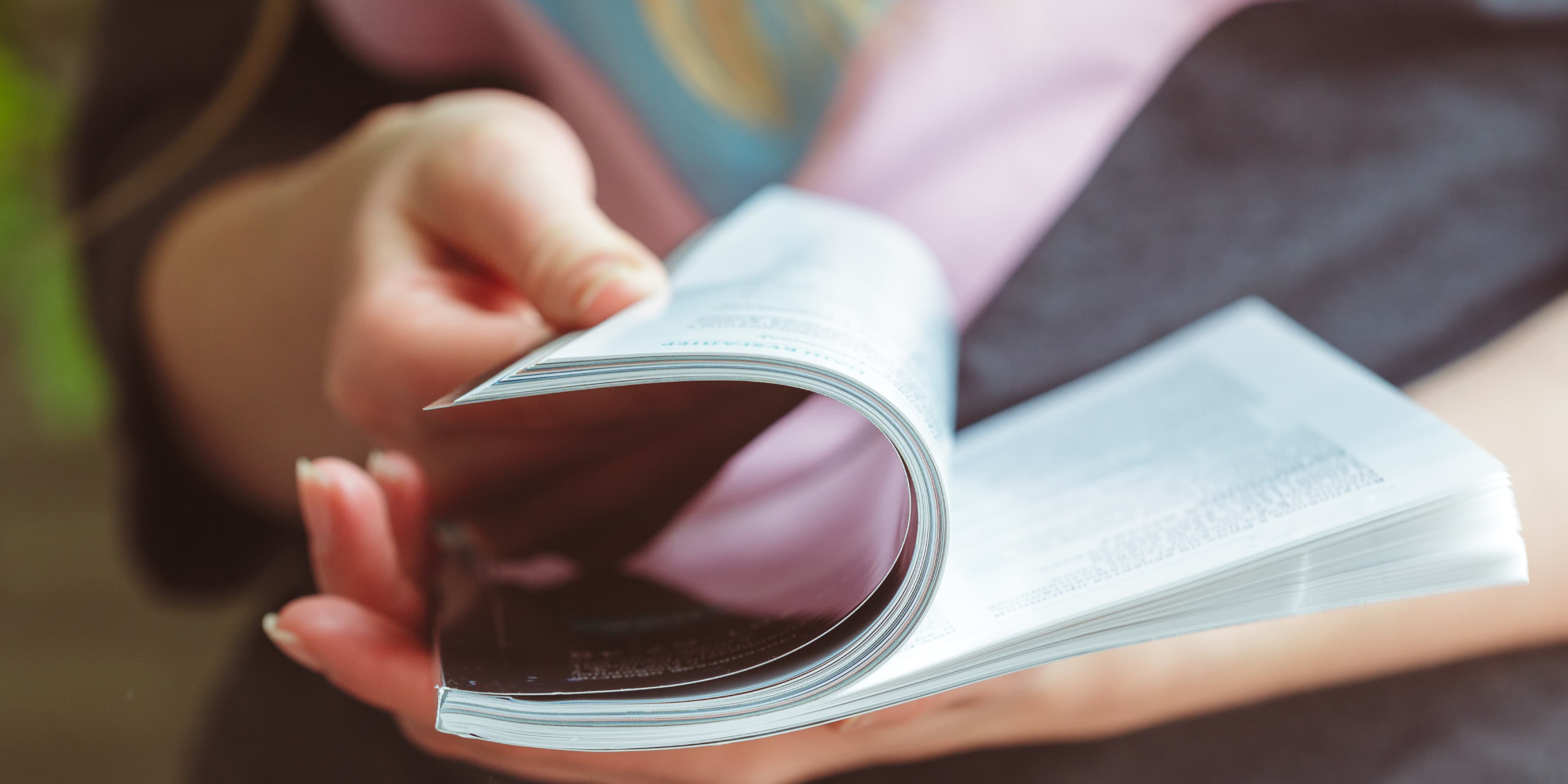 Close-up hands holding and reading a magazine