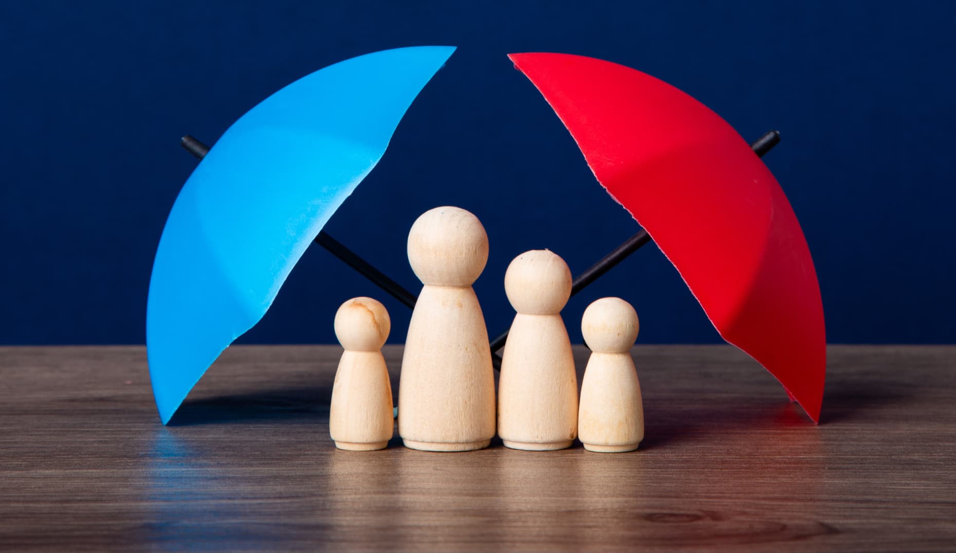 Generali — wooden family figures sheltered by umbrellas